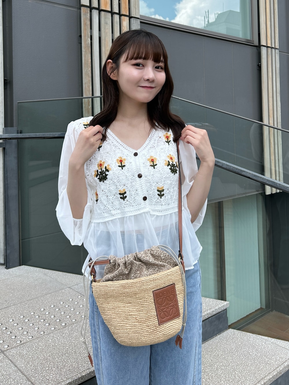 ブルー系のデニムパンツ、グレー系のスニーカー、ベージュ系のかごバッグを着用したレディースの夏コーディネートの5枚目の写真