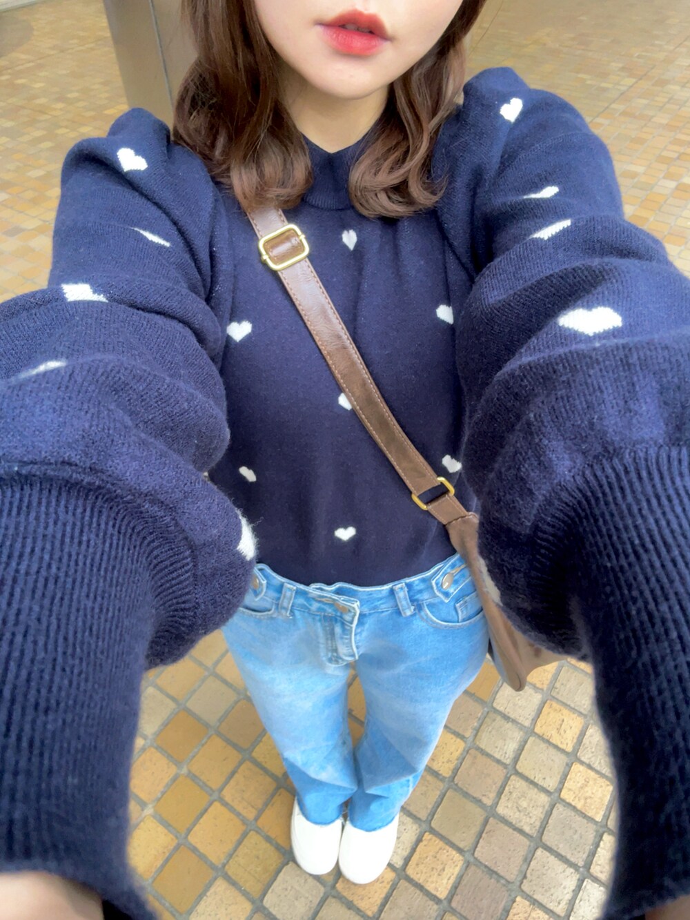 ブルー系のニット/セーター、ブラウン系のショルダーバッグ、ブルー系のデニムパンツを着用したレディースの春コーディネートの5枚目の写真