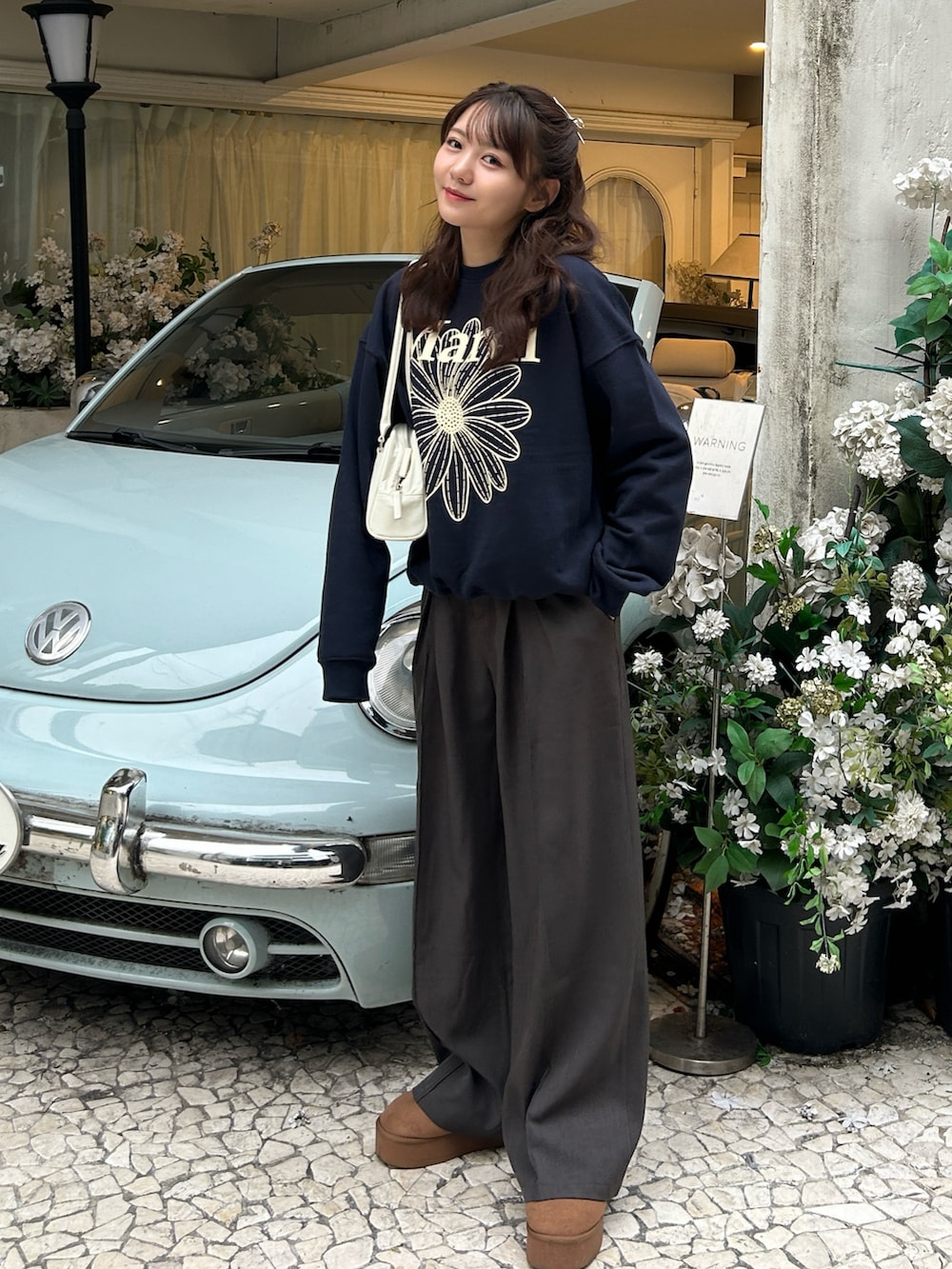 グレー系のスラックス、イエロー系のブーツ、ブルー系のスウェットを着用したレディースの秋コーディネートの2枚目の写真