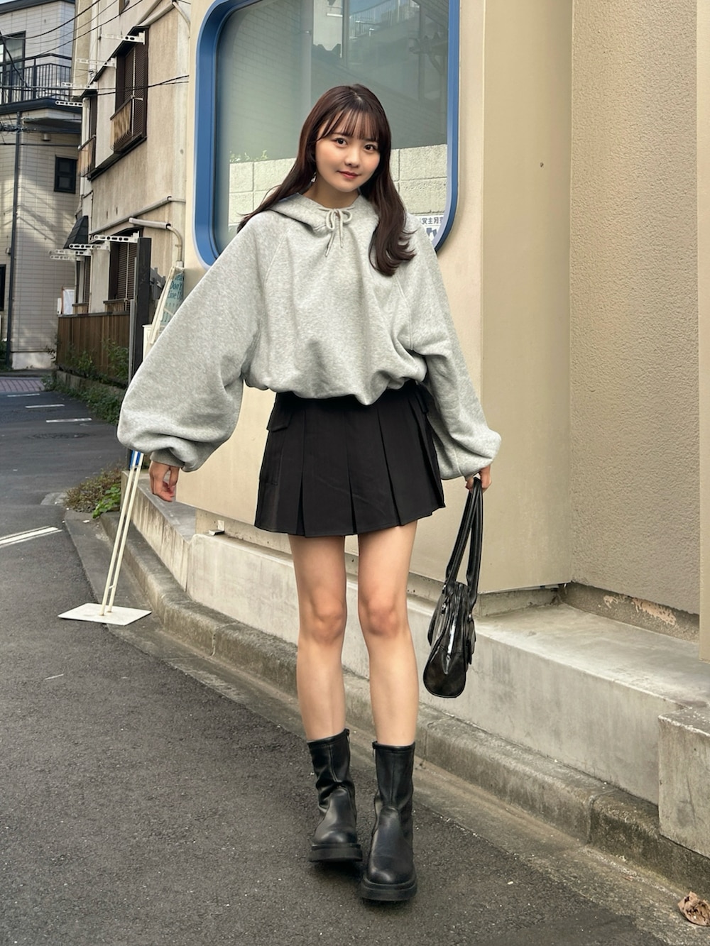 グレー系のパーカー、ブラック系のブルゾン、ブラック系のスカートを着用したレディースの秋コーディネートの3枚目の写真