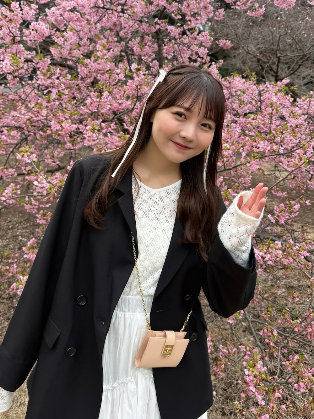 ブラック系のテーラードジャケット、ホワイト系のスカート、ブラック系のスニーカーを着用したレディースの春コーディネートの2枚目の写真