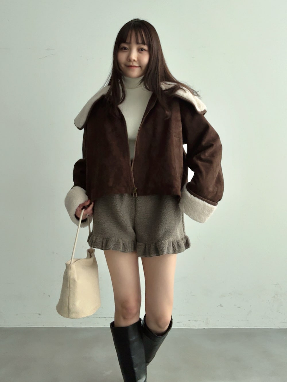 ホワイト系のショルダーバッグ、ブラック系のブーツ、グレー系のその他パンツを着用したレディースの冬コーディネートの3枚目の写真