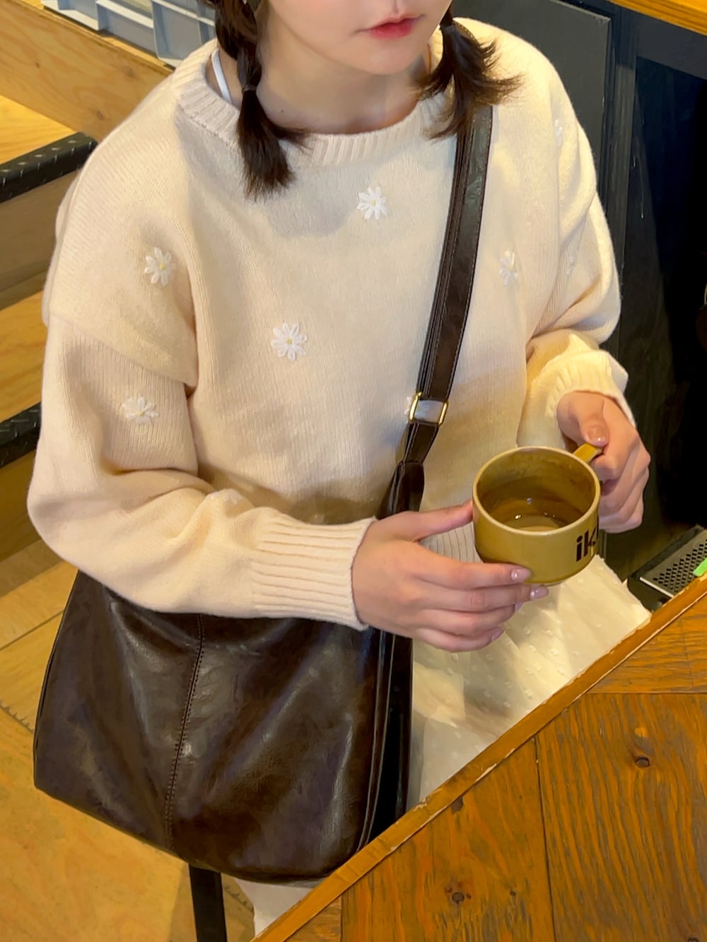 ピンク系のニット/セーター、ブラウン系のショルダーバッグ、ホワイト系のスカートを着用したレディースの冬コーディネートの2枚目の写真