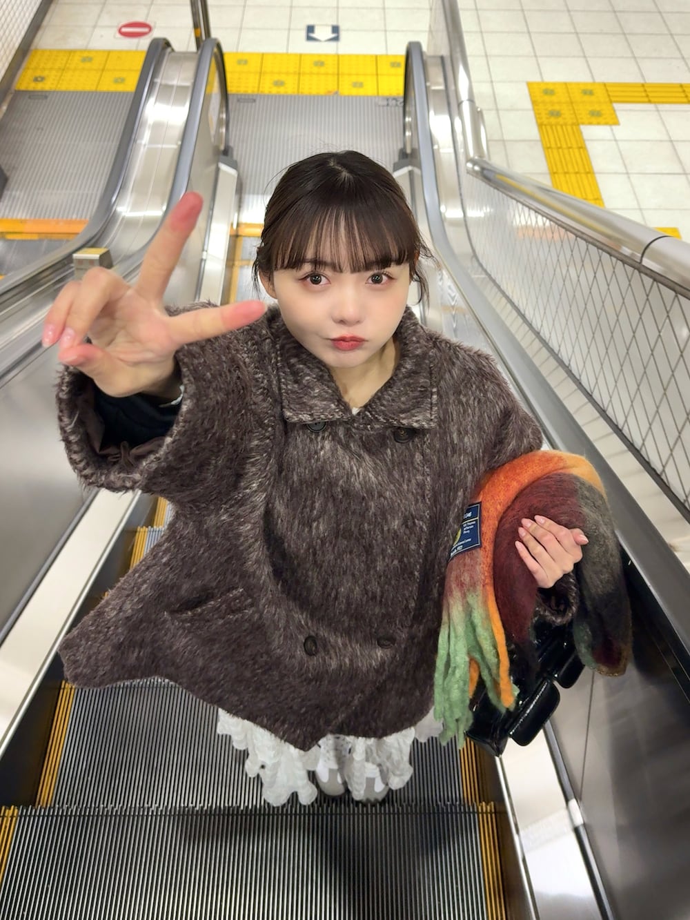 ブラウン系のピーコート、ホワイト系のワンピース、ブラック系のショルダーバッグを着用したレディースの冬コーディネートの4枚目の写真