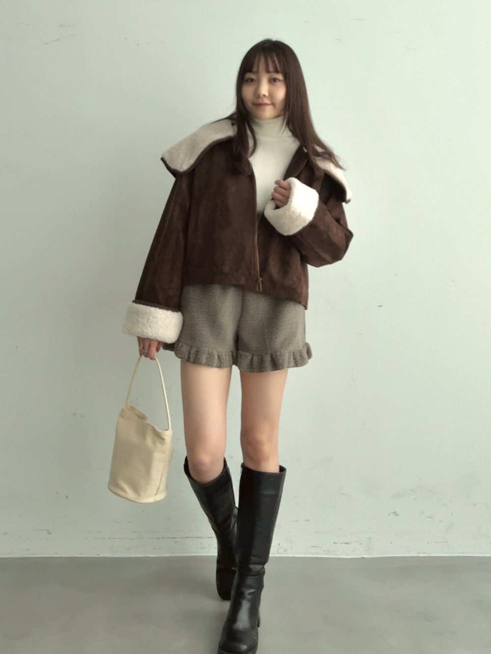 ホワイト系のショルダーバッグ、ブラック系のブーツ、グレー系のその他パンツを着用したレディースの冬コーディネートの2枚目の写真