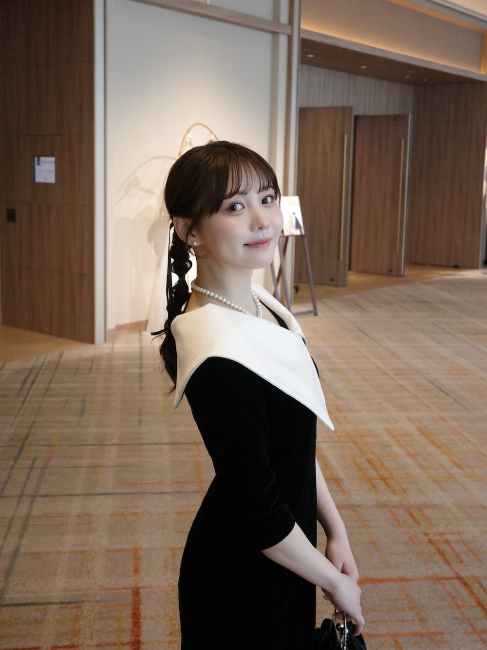 ブラック系のパンプス、ブラック系のドレス、ブラック系のハンドバッグを着用したレディースの夏コーディネートの2枚目の写真