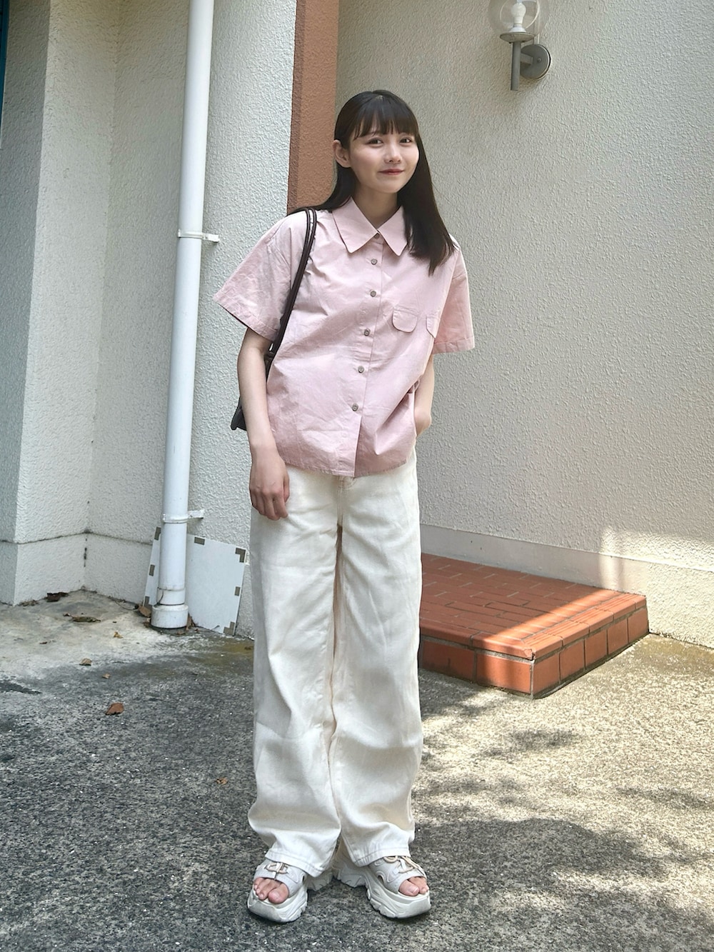 ピンク系のシャツ/ブラウス、ブラウン系のハンドバッグ、ホワイト系のパンツを着用したレディースの夏コーディネートの2枚目の写真