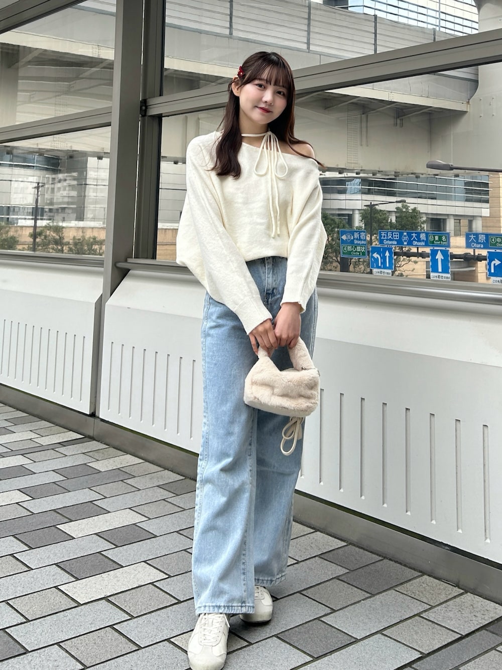 ブラック系のステンカラーコート、ホワイト系のハンドバッグ、ブルー系のデニムパンツを着用したレディースの冬コーディネートの3枚目の写真