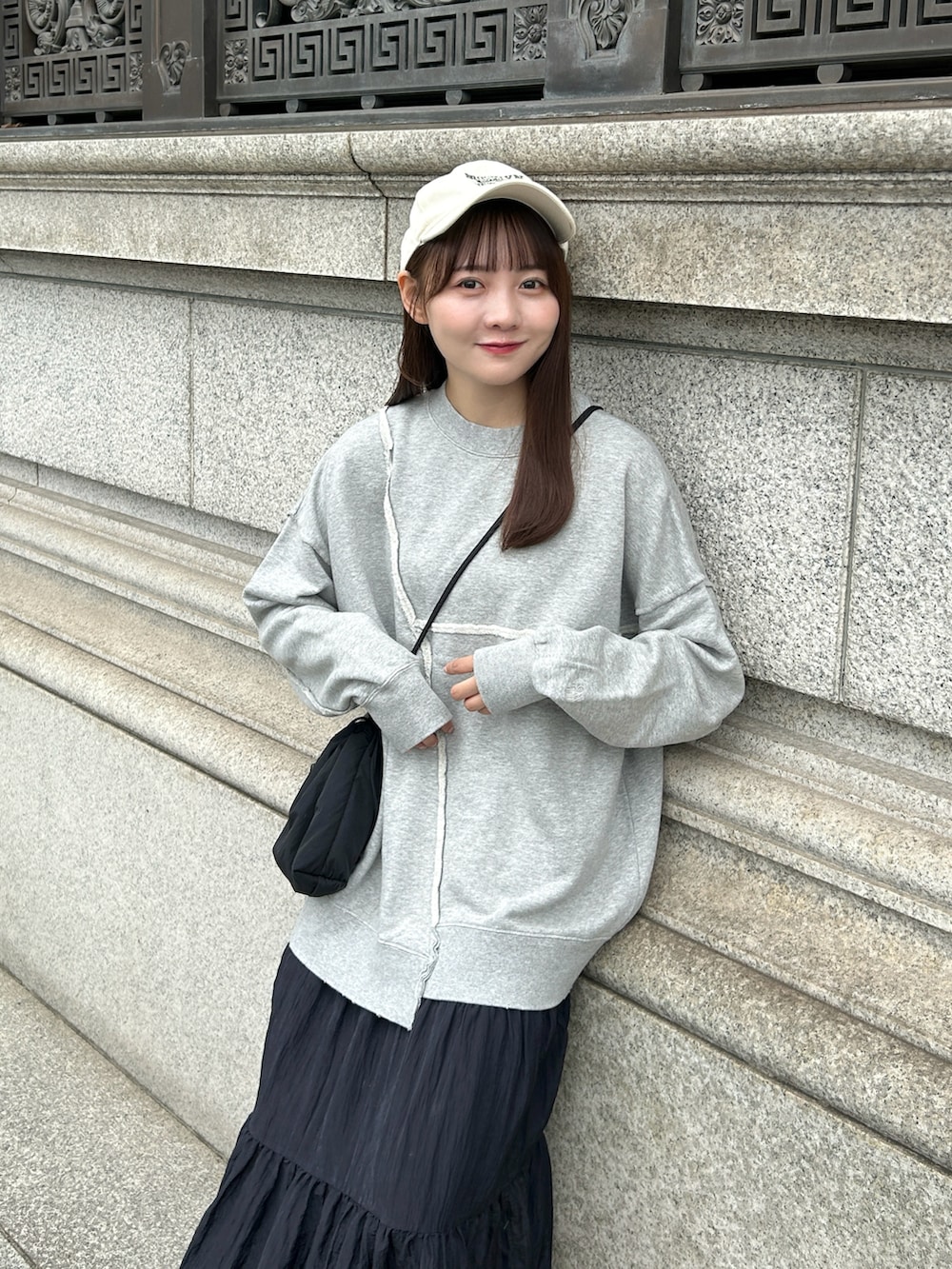 グレー系のスウェット、ブラック系のバッグ、ブラック系のスカートを着用したレディースの秋コーディネートの3枚目の写真