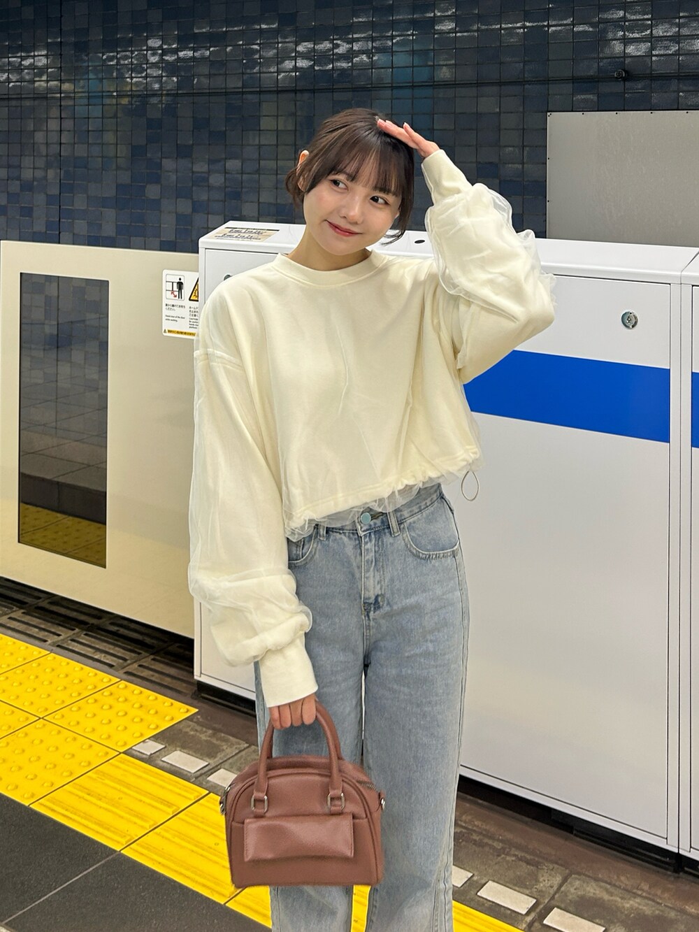 ピンク系のボストンバッグ、ブルー系のデニムパンツ、ベージュ系のステンカラーコートを着用したレディースの冬コーディネートの3枚目の写真