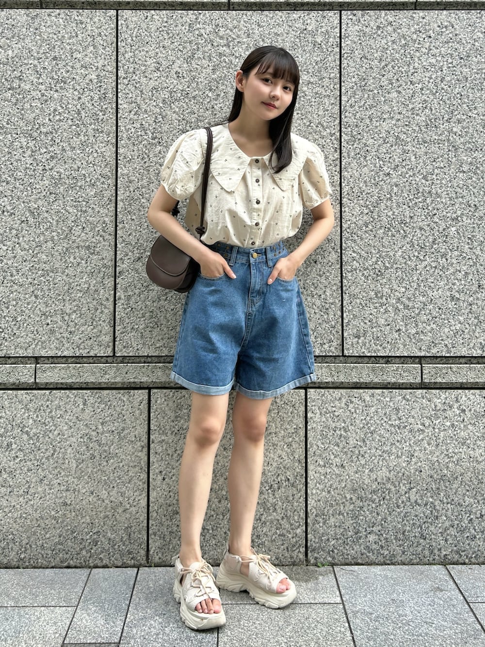 ブルー系のシャツ/ブラウス、ブルー系のデニムパンツ、ブラウン系のハンドバッグを着用したレディースの夏コーディネートの2枚目の写真