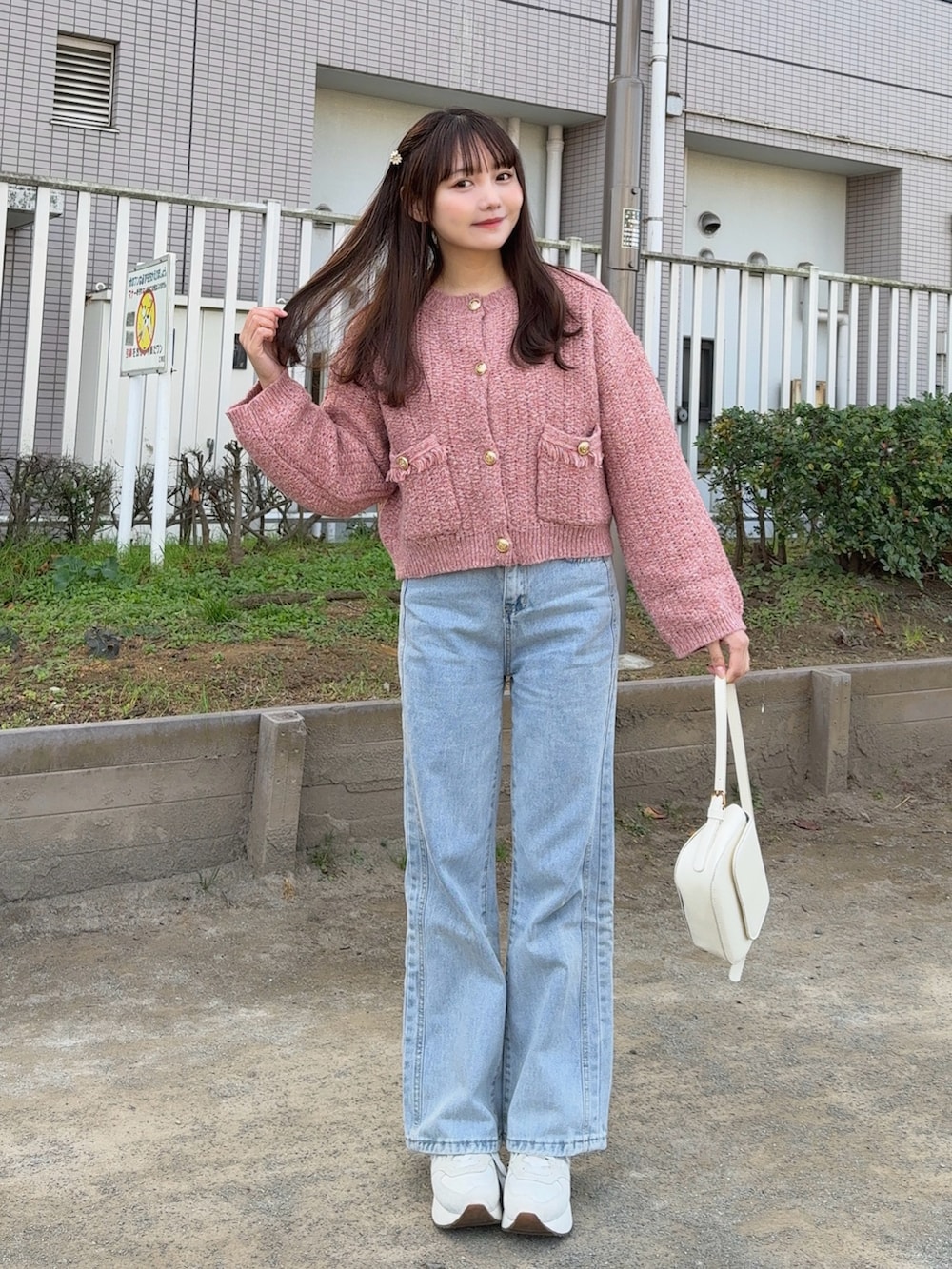 レッド系のカーディガン/ボレロ、ブラウン系のステンカラーコート、ブルー系のデニムパンツを着用したレディースの冬コーディネートの3枚目の写真