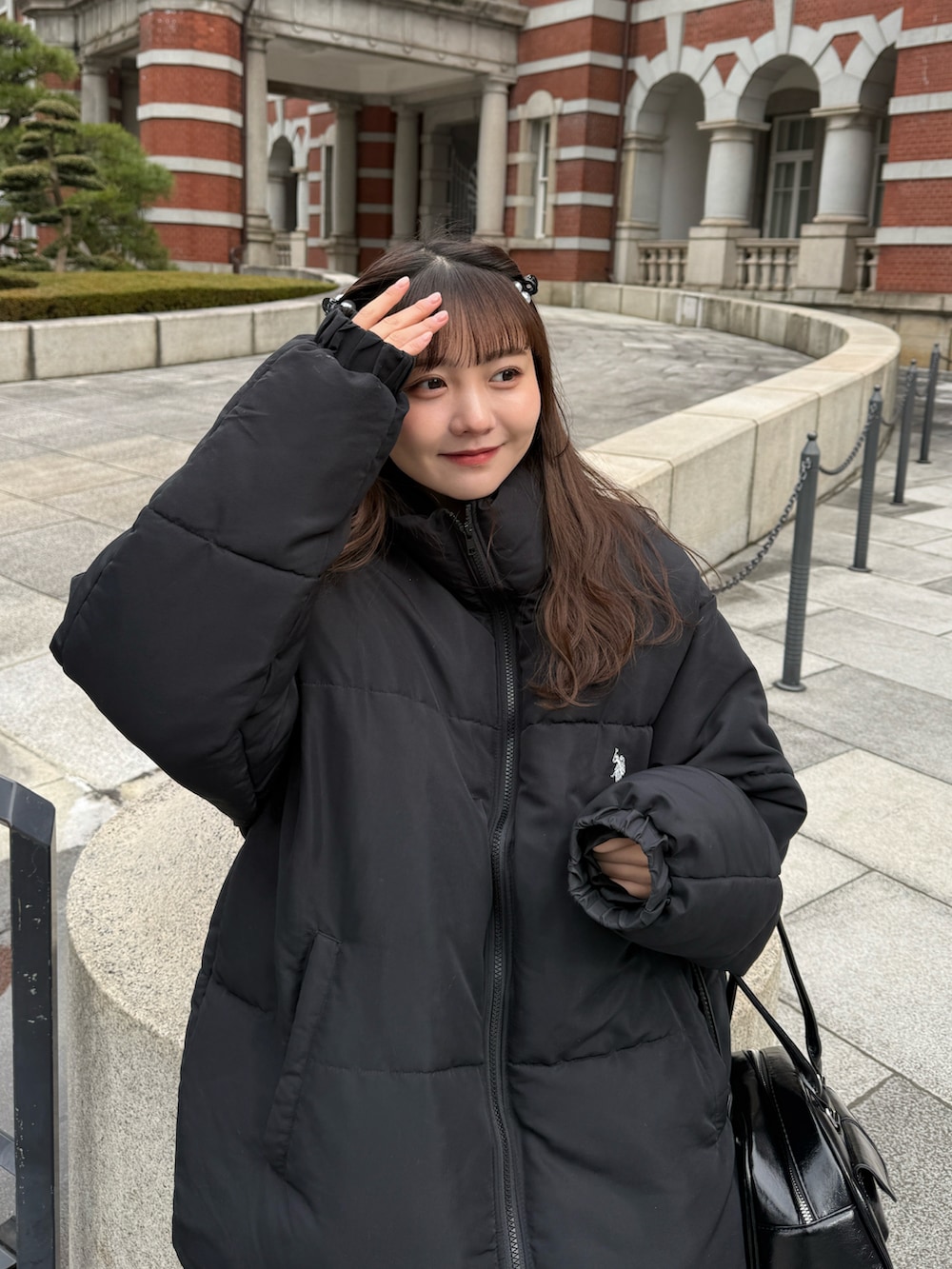 イエロー系のブーツ、ブラック系のダウンジャケット/コート、ブラック系のショルダーバッグを着用したレディースの冬コーディネートの5枚目の写真