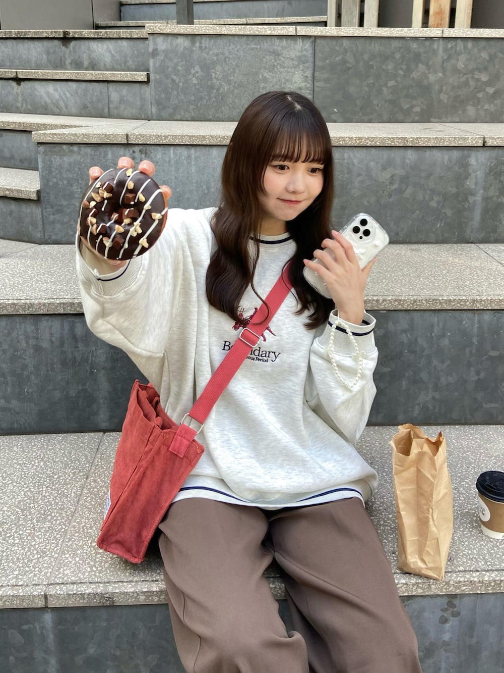 レッド系のショルダーバッグ、ベージュ系のスウェット、ブラウン系のその他パンツを着用したレディースの冬コーディネートの3枚目の写真