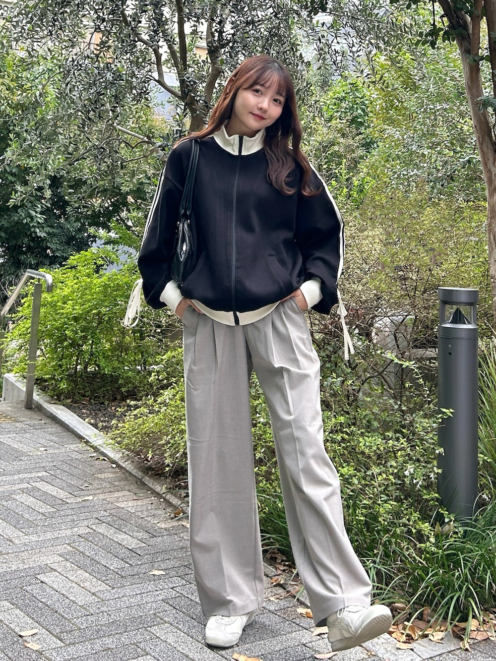 ブラック系のジャージ、ブラック系のバッグ、ベージュ系のパンツを着用したレディースの秋コーディネートの5枚目の写真