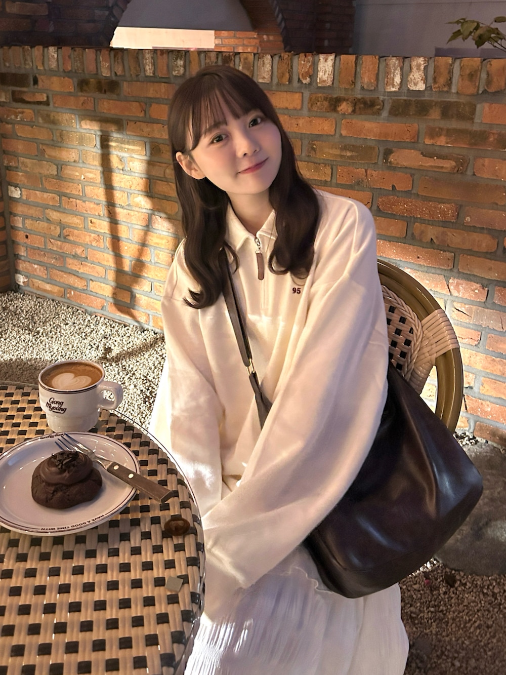 ブラウン系のショルダーバッグ、ホワイト系のスウェット、ホワイト系のワンピースを着用したレディースの秋コーディネートの5枚目の写真