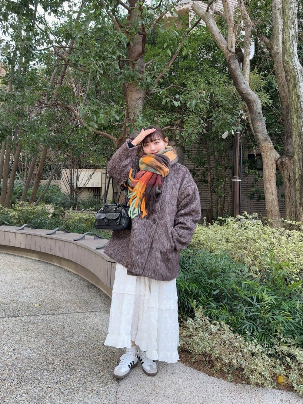 ブラウン系のピーコート、ホワイト系のワンピース、ブラック系のショルダーバッグを着用したレディースの冬コーディネートの2枚目の写真