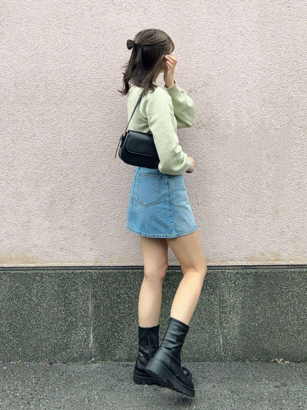 グリーン系のニット/セーター、ブルー系のデニムスカート、ブラック系のブーツを着用したレディースの春コーディネートの4枚目の写真