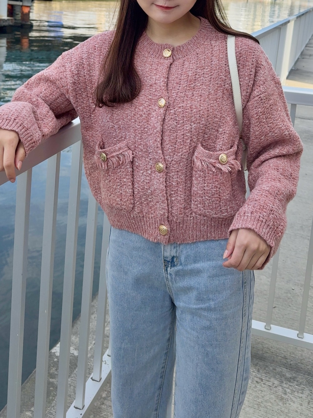 レッド系のカーディガン/ボレロ、ブラウン系のステンカラーコート、ブルー系のデニムパンツを着用したレディースの冬コーディネートの4枚目の写真