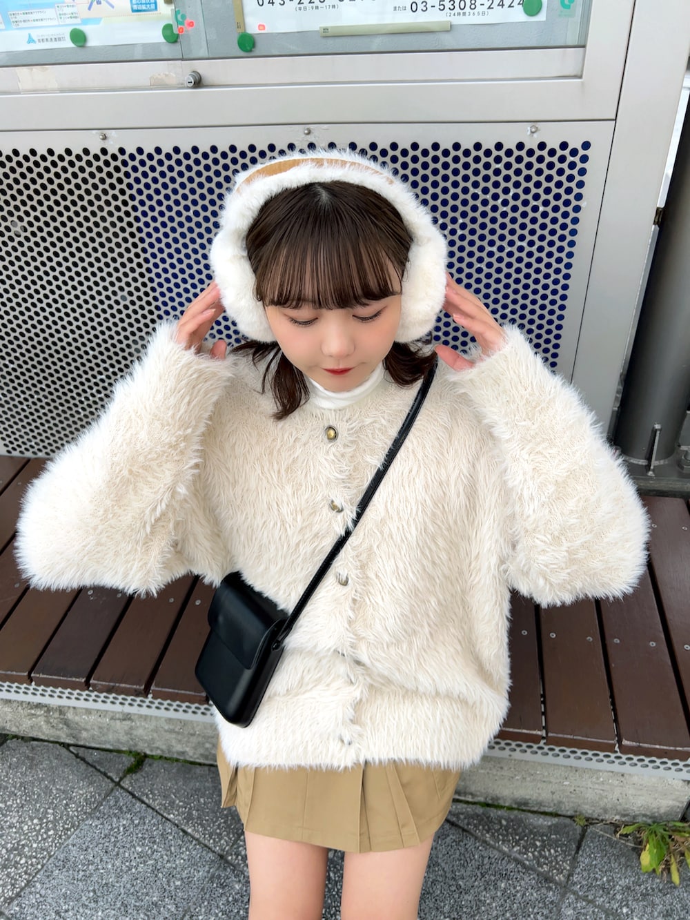 ブラック系のブーツ、ベージュ系のスカート、ブラック系のショルダーバッグを着用したレディースの冬コーディネートの2枚目の写真