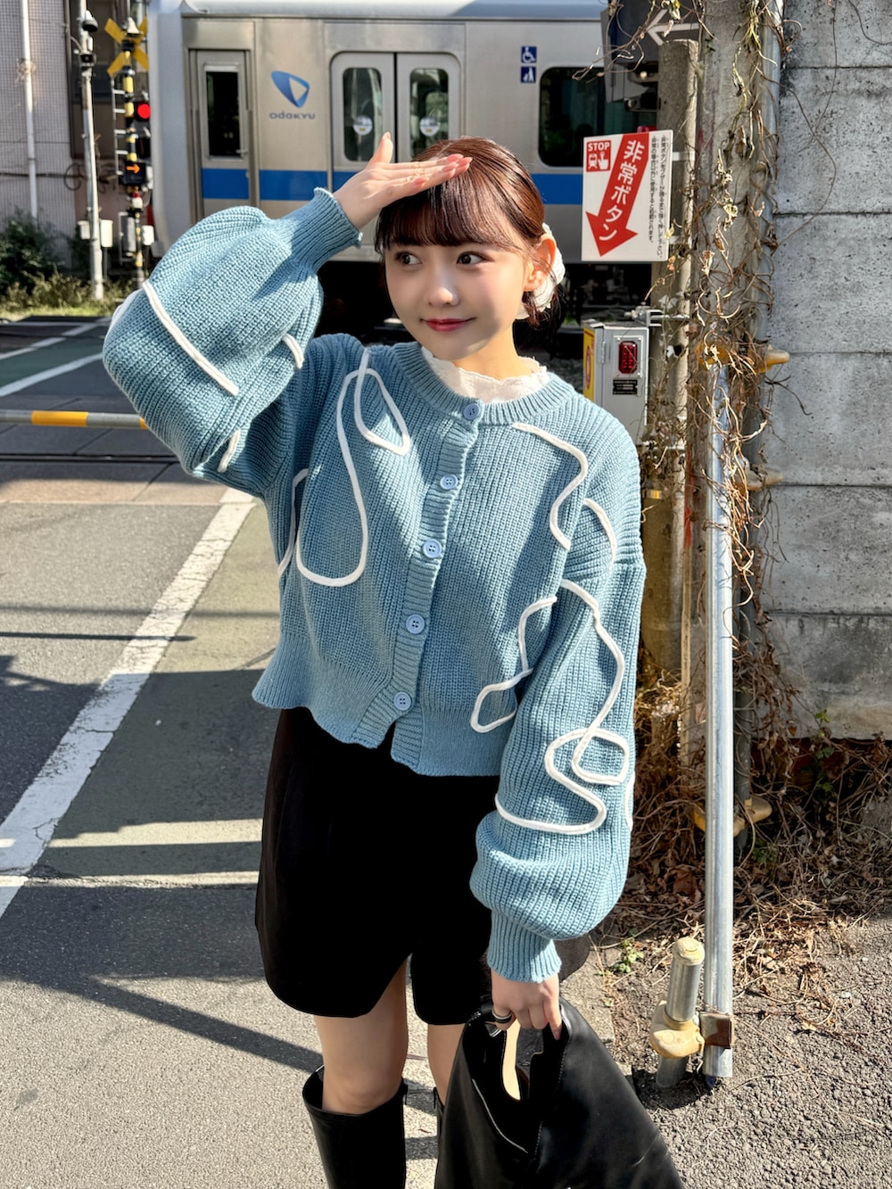 ブルー系のカーディガン/ボレロ、ホワイト系のTシャツ/カットソー、ブラック系のハンドバッグを着用したレディースの冬コーディネートの2枚目の写真