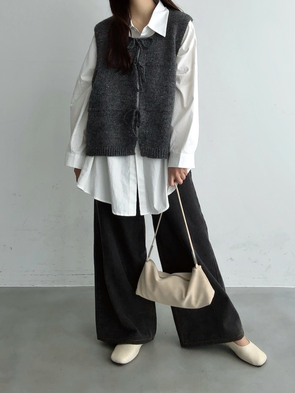 グレー系のベスト、ブラック系のその他パンツ、ホワイト系のショルダーバッグを着用したレディースの秋コーディネートの4枚目の写真