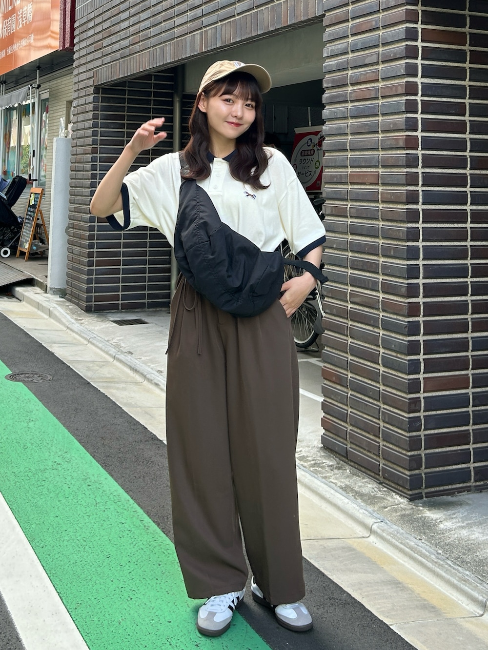 ホワイト系のポロシャツ、ブラウン系のその他パンツ、ブラック系のショルダーバッグを着用したレディースの夏コーディネートの4枚目の写真