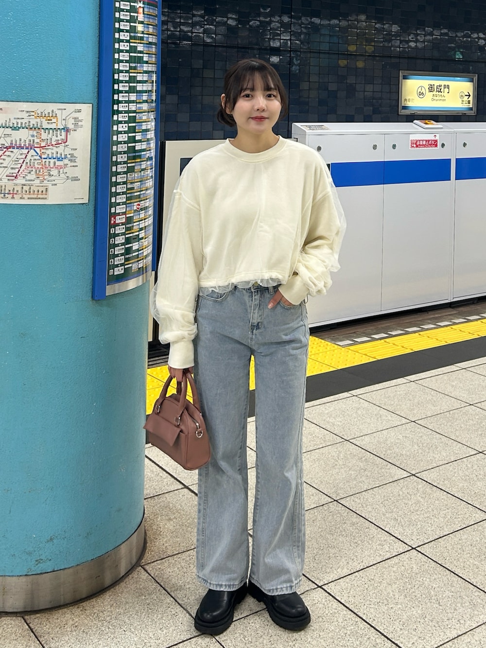 ピンク系のボストンバッグ、ブルー系のデニムパンツ、ベージュ系のステンカラーコートを着用したレディースの冬コーディネートの4枚目の写真