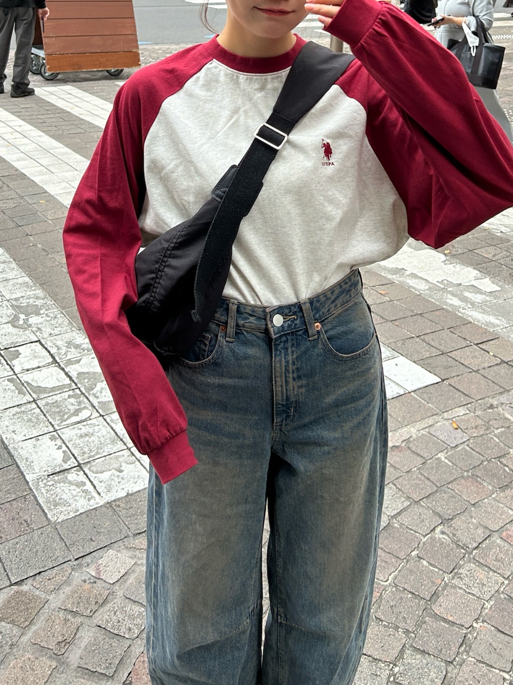 レッド系のTシャツ/カットソー、ブラック系のショルダーバッグ、ブルー系のデニムパンツを着用したレディースの秋コーディネートの2枚目の写真