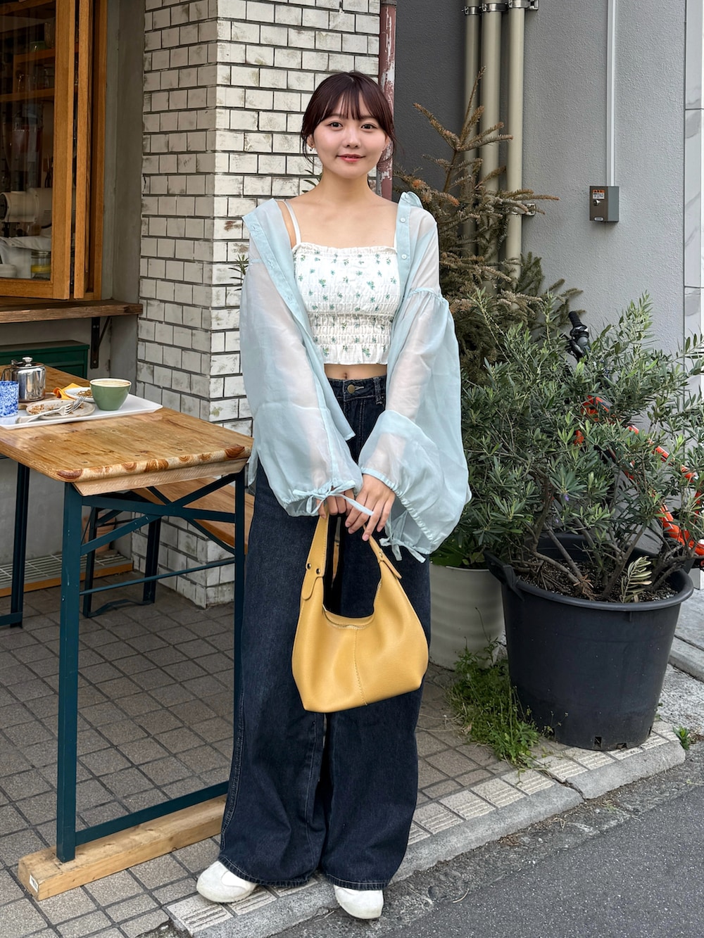グリーン系のシャツ/ブラウス、イエロー系のハンドバッグ、ブルー系のデニムパンツを着用したレディースの夏コーディネートの3枚目の写真