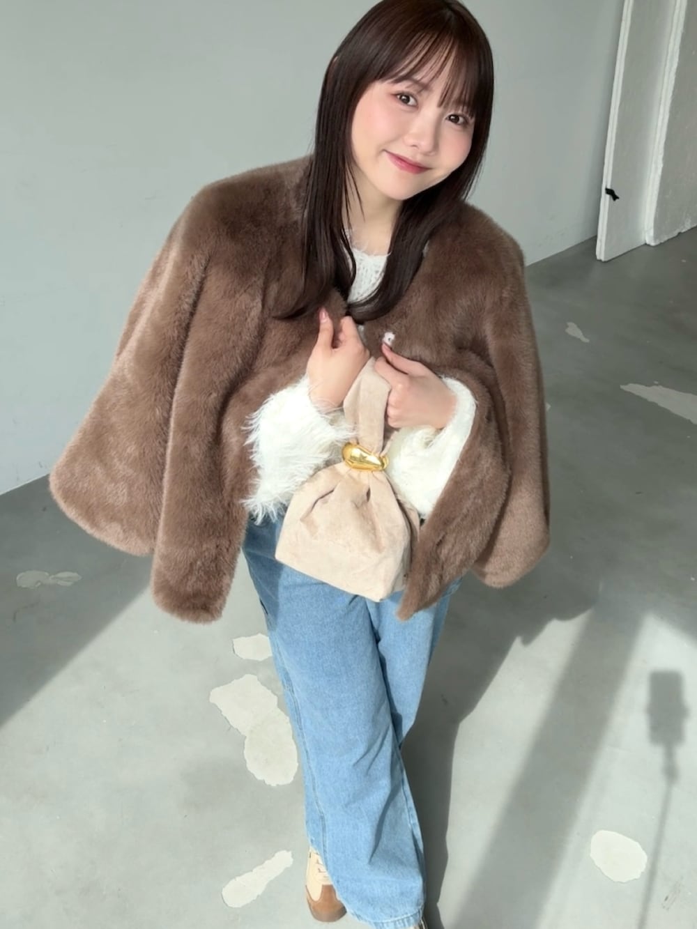 ホワイト系のニット/セーター、ブラウン系のブルゾン、ブルー系のデニムパンツを着用したレディースの春コーディネートの4枚目の写真