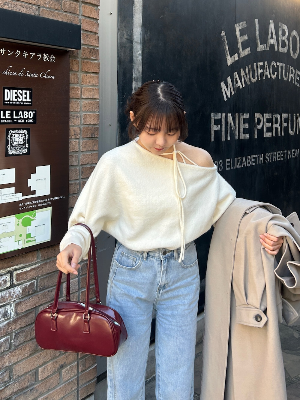 ホワイト系のニット/セーター、ベージュ系のステンカラーコート、ブルー系のデニムパンツを着用したレディースの冬コーディネートの3枚目の写真