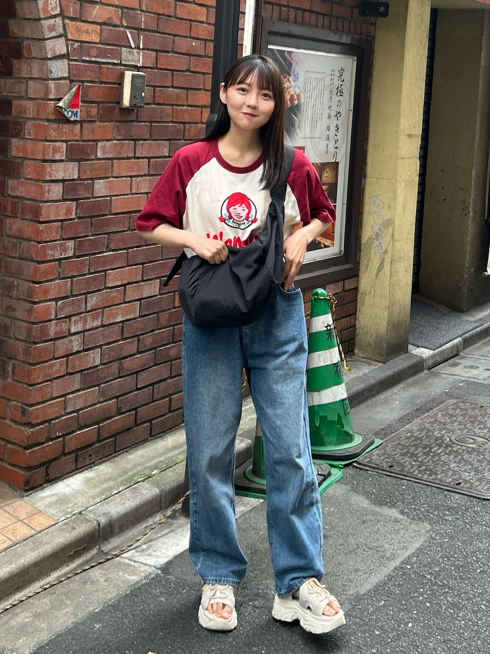 ベージュ系のサンダル、ブルー系のデニムパンツ、ブラック系のショルダーバッグを着用したレディースの夏コーディネートの2枚目の写真