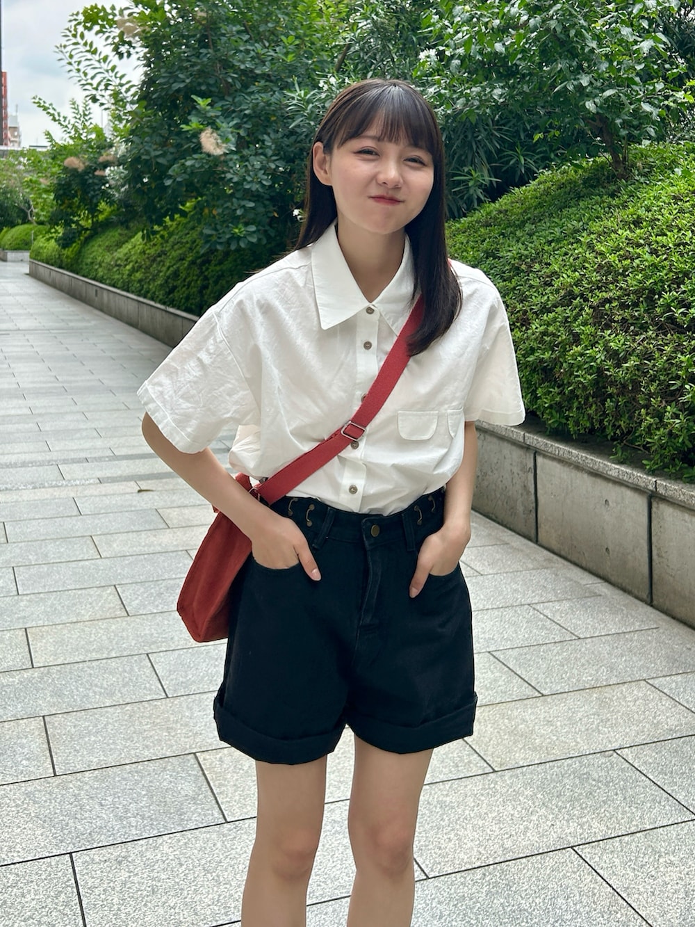 レッド系のショルダーバッグ、ベージュ系のサンダル、ホワイト系のシャツ/ブラウスを着用したレディースの夏コーディネートの4枚目の写真