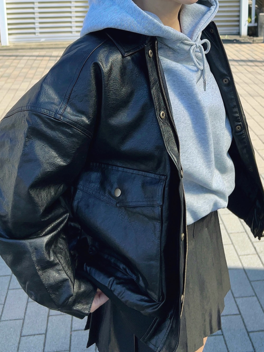 グレー系のパーカー、ブラック系のブルゾン、ブラック系のスカートを着用したレディースの冬コーディネートの2枚目の写真