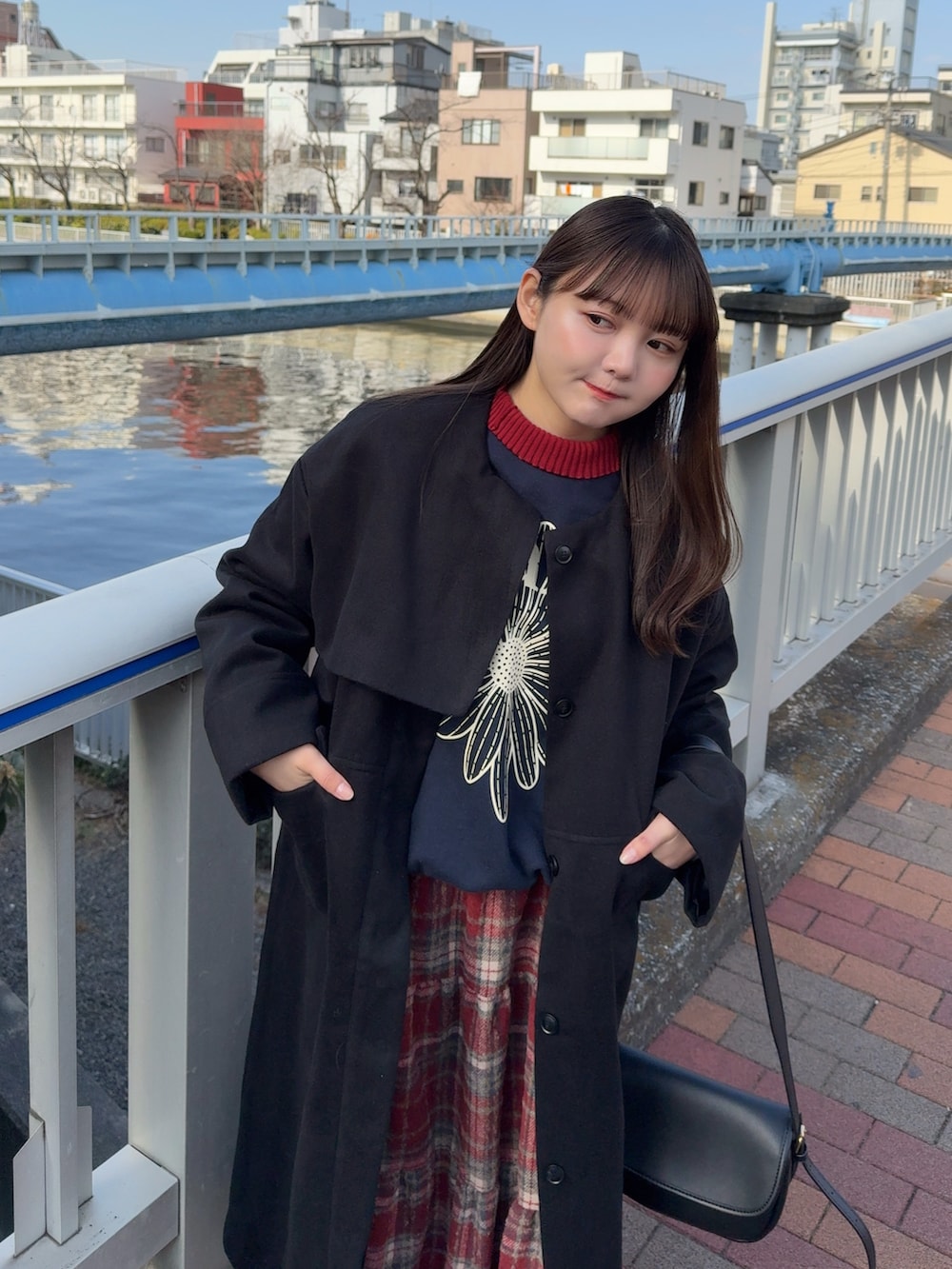 ブラック系のノーカラーコート、ブルー系のスウェット、レッド系のニット/セーターを着用したレディースの冬コーディネートの2枚目の写真