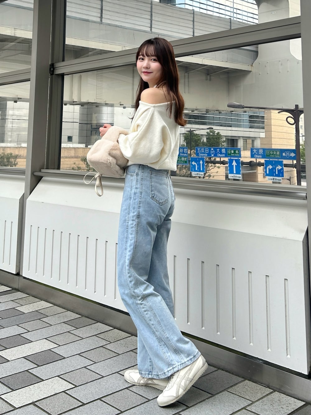 ブラック系のステンカラーコート、ホワイト系のハンドバッグ、ブルー系のデニムパンツを着用したレディースの冬コーディネートの5枚目の写真