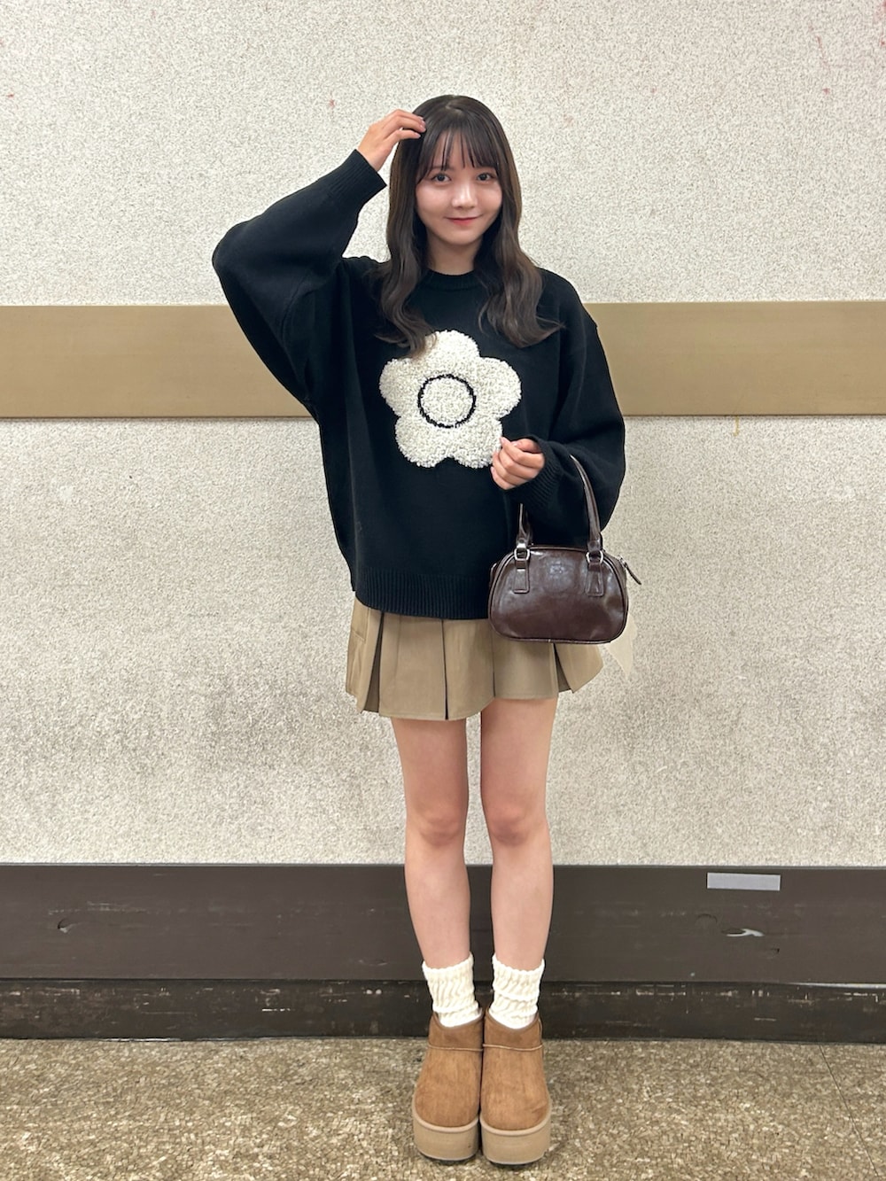 ブラウン系のハンドバッグ、ベージュ系のブーツ、ベージュ系のスカートを着用したレディースの秋コーディネートの2枚目の写真