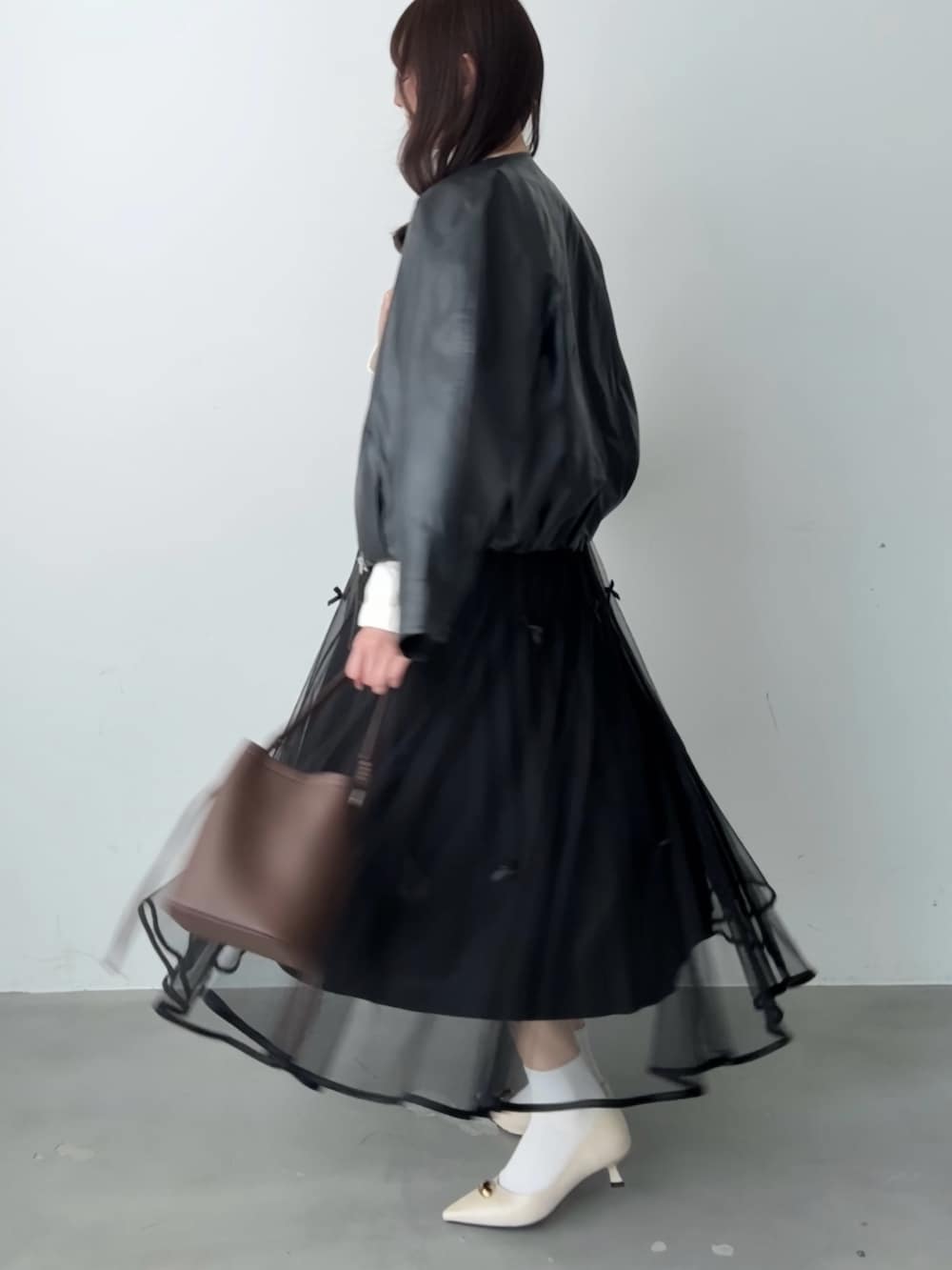 ホワイト系のシャツ/ブラウス、ブラック系のスカート、ブラウン系のハンドバッグを着用したレディースの春コーディネートの5枚目の写真