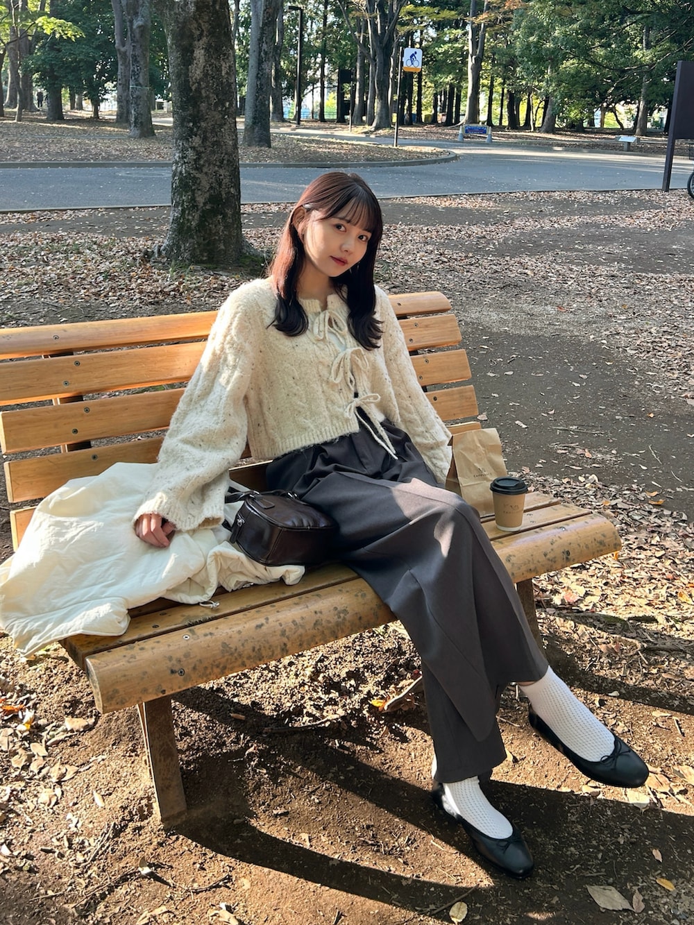 ブラウン系のハンドバッグ、ブラック系のバレエシューズ、グレー系のスラックスを着用したレディースの秋コーディネートの3枚目の写真