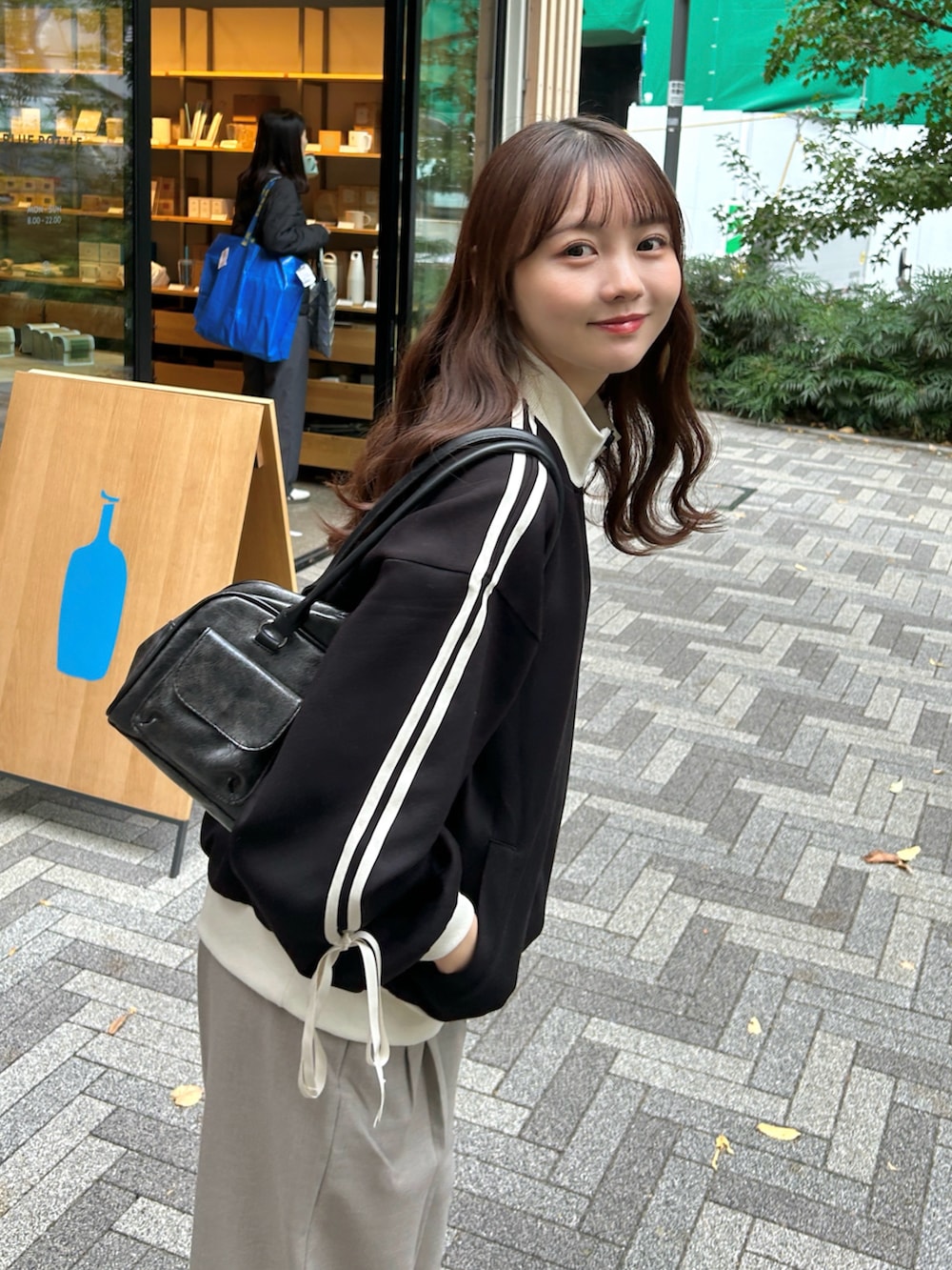 ブラック系のジャージ、ブラック系のバッグ、ベージュ系のパンツを着用したレディースの秋コーディネートの4枚目の写真