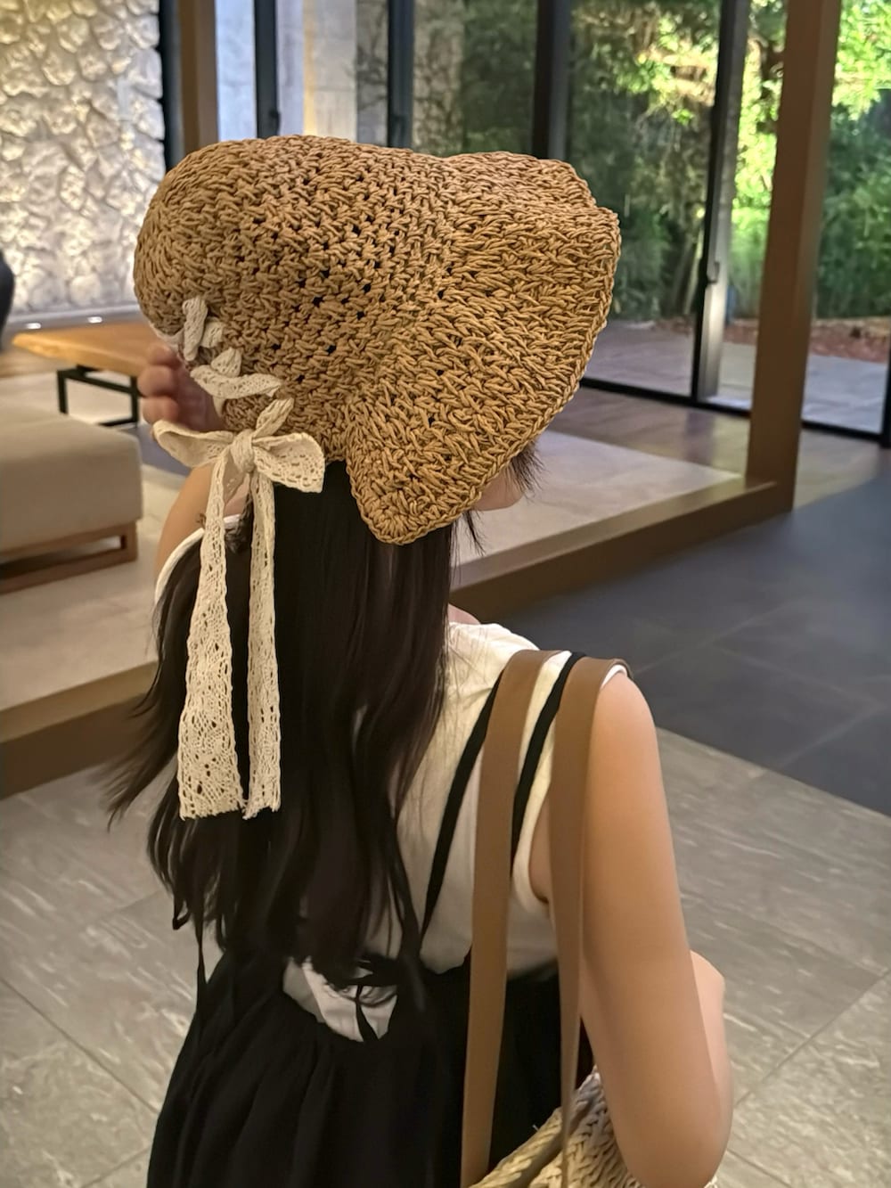 ブラウン系のパンプス、ブラック系のワンピース、ホワイト系のかごバッグを着用したレディースの夏コーディネートの4枚目の写真