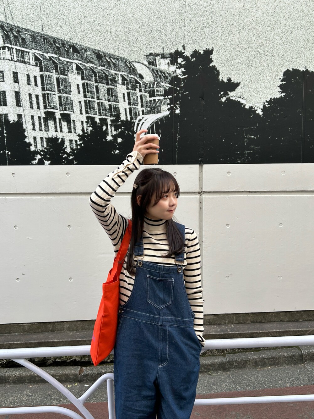 ブルー系のサロペット/オーバーオール、ホワイト系のニット/セーター、オレンジ系のトートバッグを着用したレディースの春コーディネートの3枚目の写真