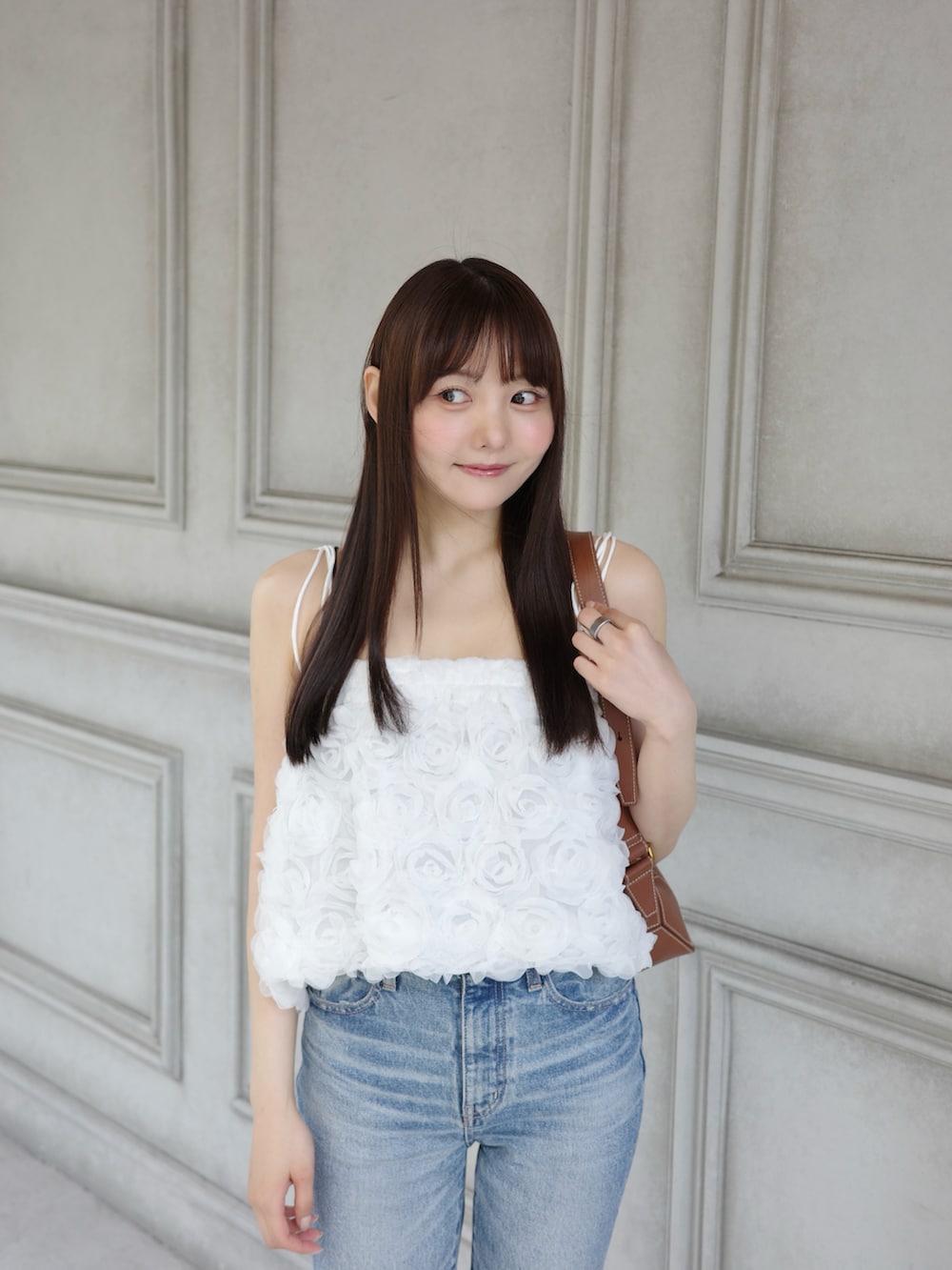 ホワイト系のキャミソール、ブルー系のデニムパンツ、ベージュ系のサンダルを着用したレディースの夏コーディネートの2枚目の写真