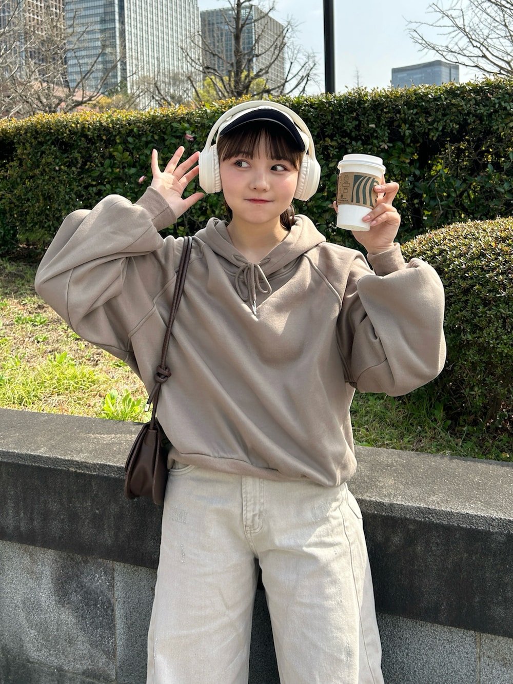 ベージュ系のデニムパンツ、ベージュ系のスニーカー、ブラウン系のハンドバッグを着用したレディースの春コーディネートの2枚目の写真
