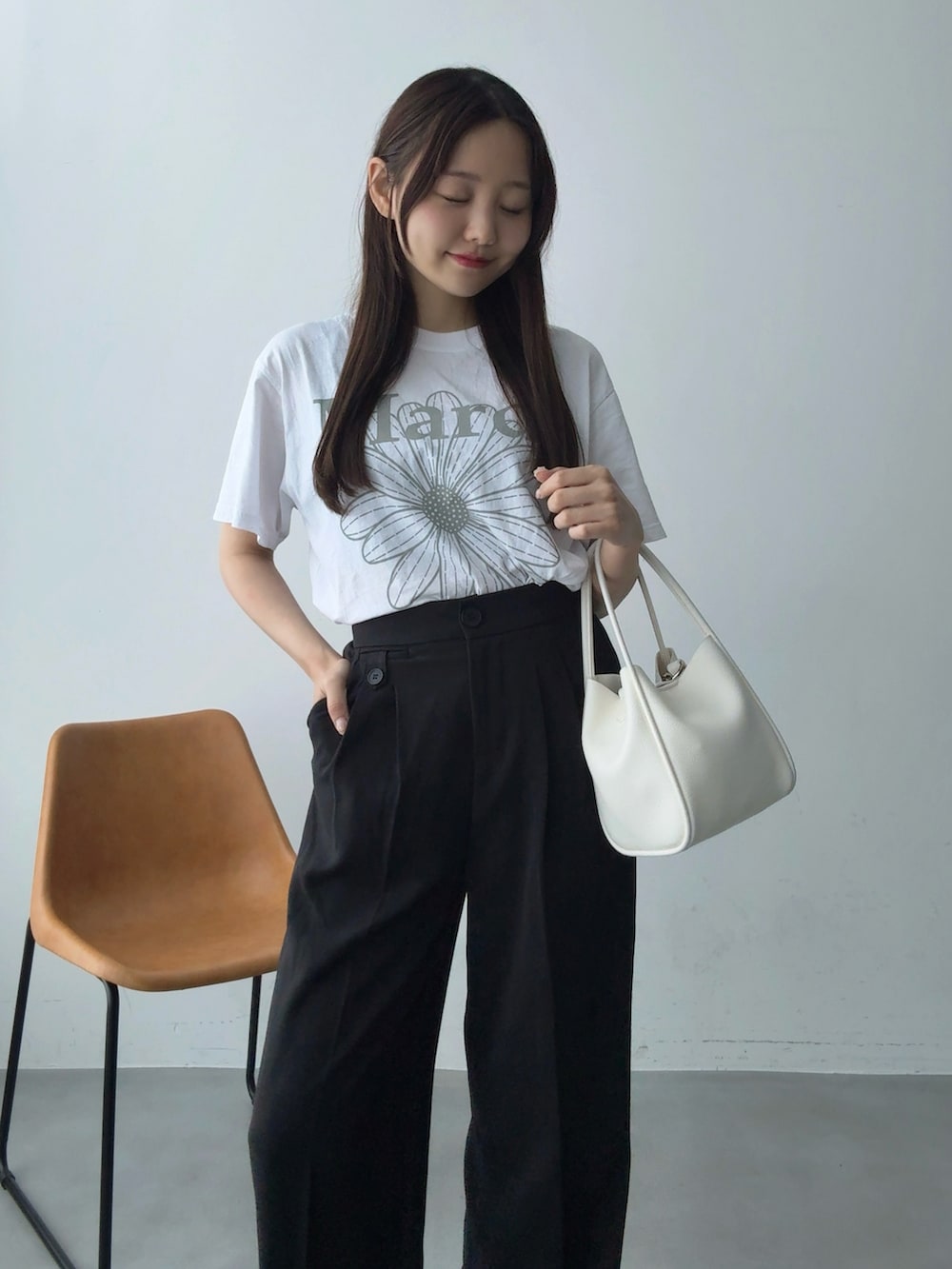 ブラック系のスラックス、ホワイト系のTシャツ/カットソー、ホワイト系のハンドバッグを着用したレディースの夏コーディネートの2枚目の写真