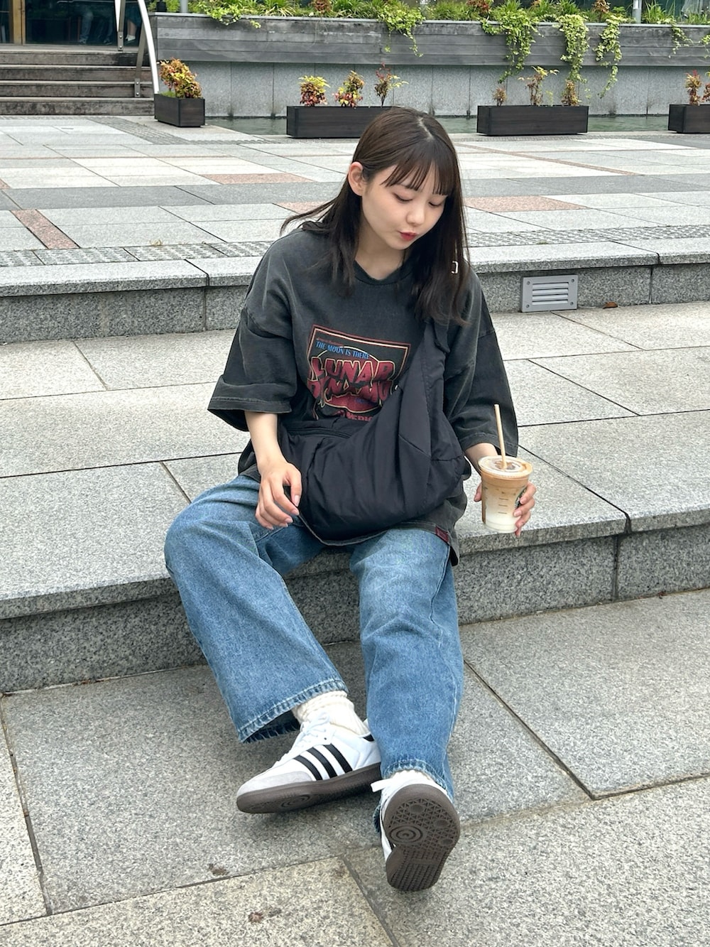 ブラック系のショルダーバッグ、ブルー系のデニムパンツ、ホワイト系のスニーカーを着用したレディースの夏コーディネートの3枚目の写真