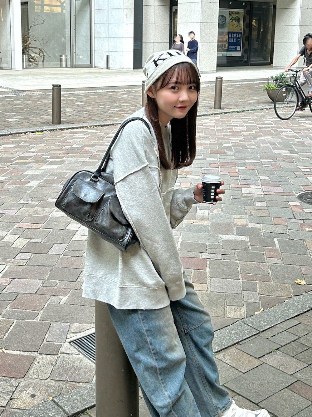 グレー系のスウェット、ブラック系のバッグ、ブルー系のデニムパンツを着用したレディースの秋コーディネートの5枚目の写真