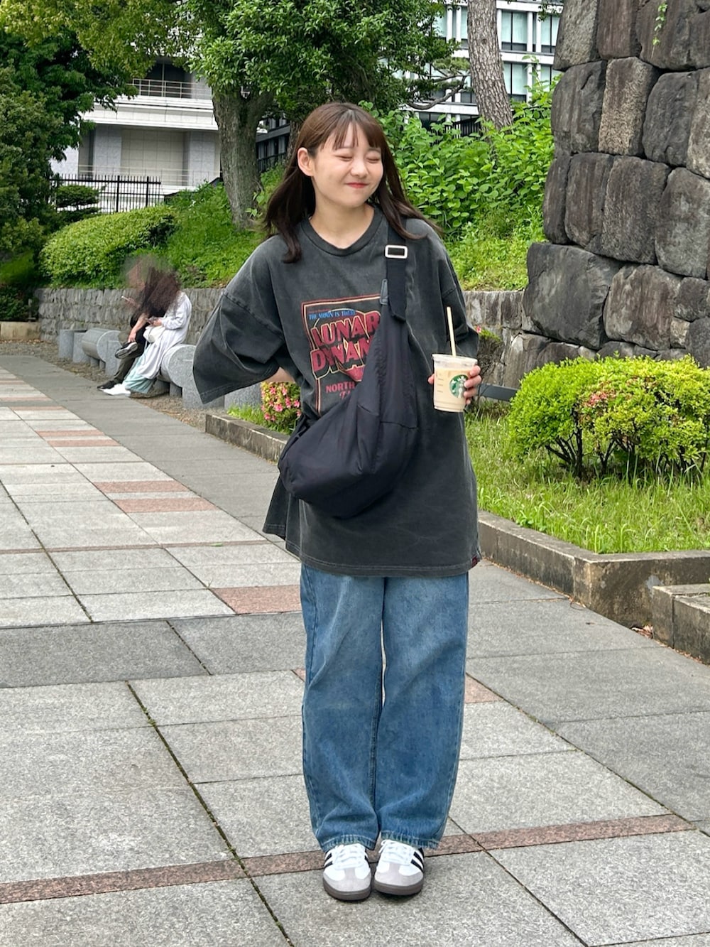 ブラック系のショルダーバッグ、ブルー系のデニムパンツ、ホワイト系のスニーカーを着用したレディースの夏コーディネートの2枚目の写真