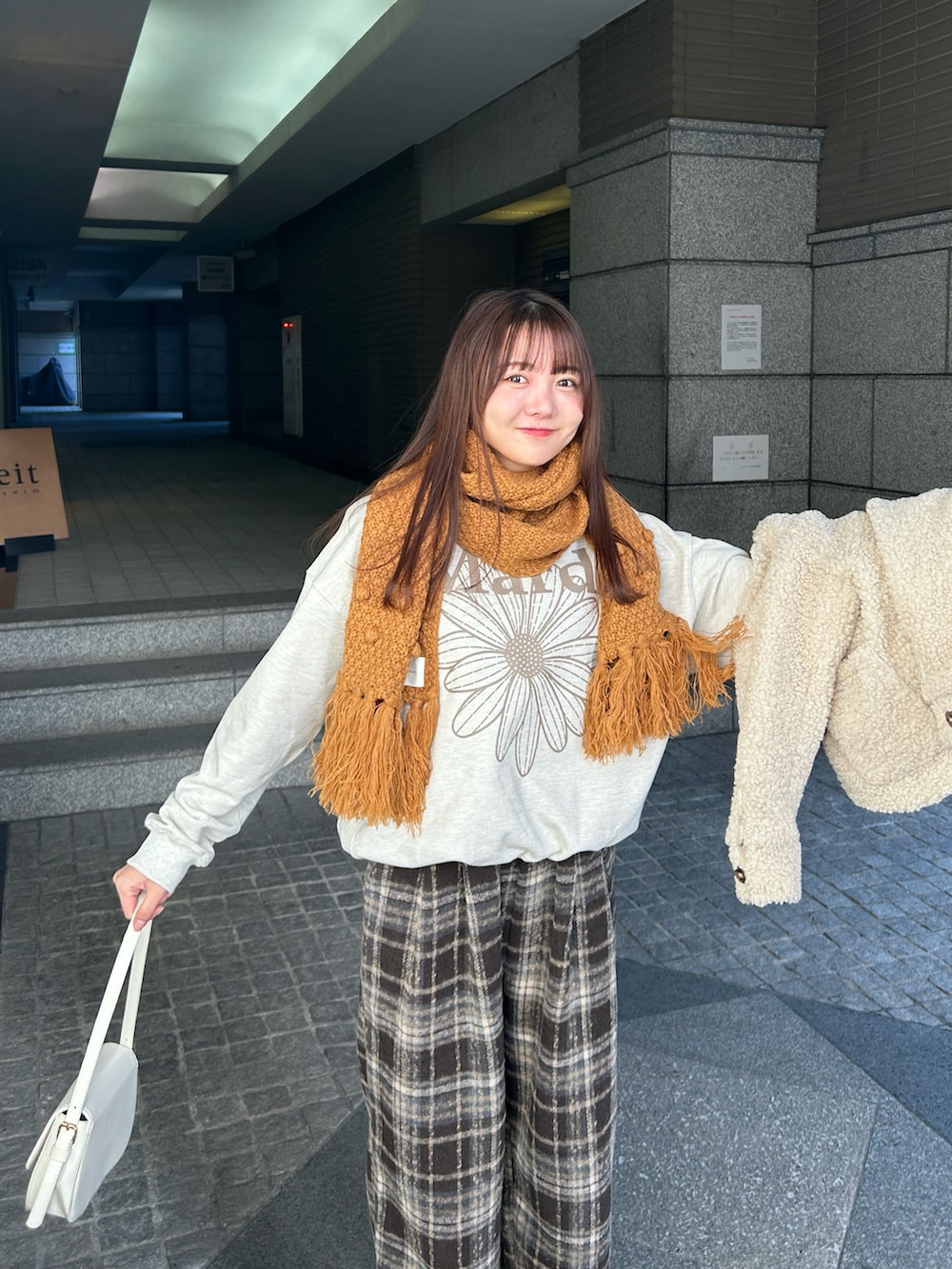 ホワイト系のハンドバッグ、ブラウン系のその他パンツ、ホワイト系のブルゾンを着用したレディースの冬コーディネートの2枚目の写真